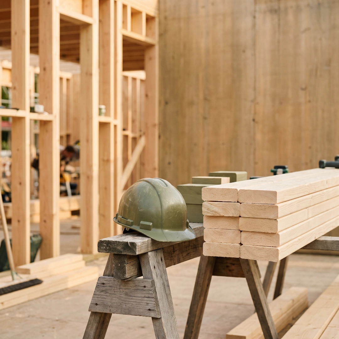 A hard hat and stacked lumber at a house construction site